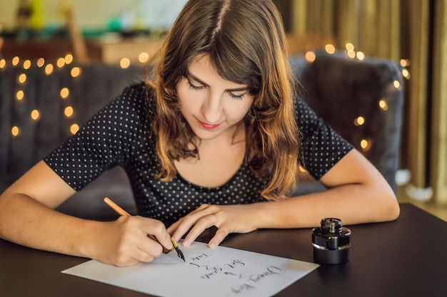 Wymarzony duży zestaw celów podejmij działanie Kaligraf młoda kobieta pisze frazę na białym papierze Wpisując ozdobne zdobione litery Kaligrafia projekt graficzny napis koncepcja tworzenia pisma ręcznego