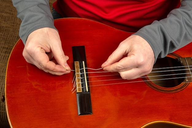 Wymiana i włożenie nylonowych strun podczas lekcji gry na gitarze klasycznej dla muzyka