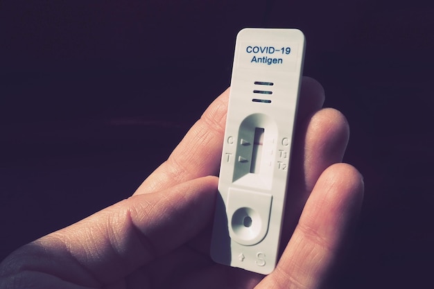 Wynik testu na COVID-19 jest ujemny, niezakażony, przy użyciu sprzętu do szybkiego testowania. Test na koronawirusa na dłoni, ciemne tło. Skopiuj miejsce. Testowanie koncepcji zakażenia choroba koronawirusowa.