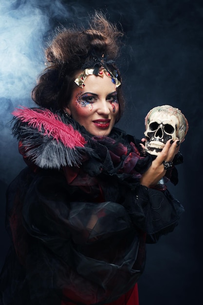 Wyobraź sobie piękną kobietę z fantazji z kreatywnym makijażem i fryzurą, trzymającą czaszkę Motyw Halloween Motyw imprezy