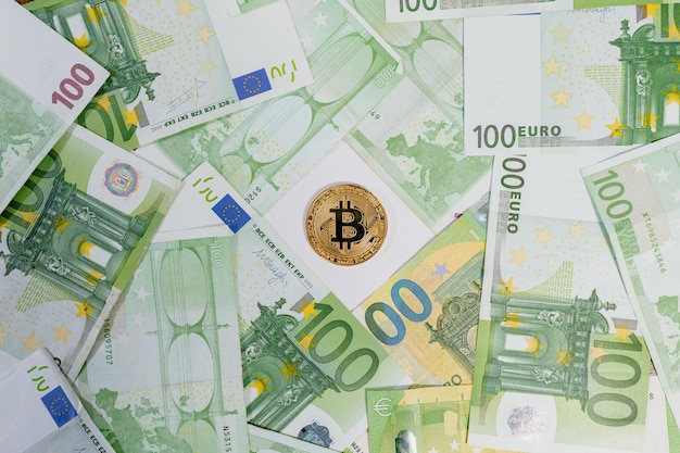 Wypełnianie Kadru Widokiem Z Góry Złotej Monety Bitcoin Fizycznej Reprezentacji W środku Wielu Banknotów Stu Euro. Wirtualna Waluta Na Pieniądze.