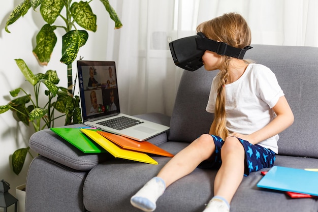 Wypróbowanie nowych technologii. Mała uczennica w dużych okularach VR jest pod wrażeniem grania w wirtualne gry. Szkoła domowa, edukacja online, edukacja domowa, koncepcja kwarantanny - Image