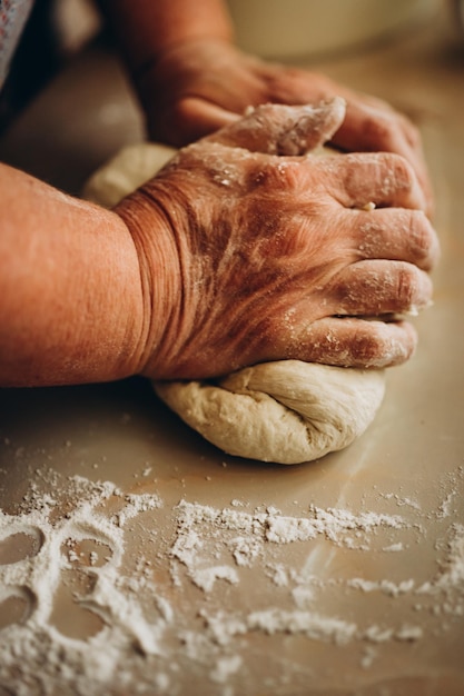 Wyrabiania ciasta przez kobiece ręce seniorów w piekarni. Koncepcja żywności.