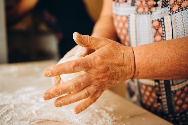 Wyrabiania ciasta przez kobiece ręce seniorów w piekarni. Koncepcja żywności.