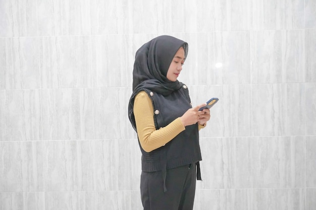 Wyraz twarzy azjatyckiej indonezyjskiej kobiety w czarnym hidżabie z żółtymi rękawami