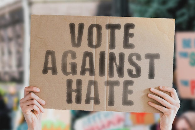 Wyrażenie Głosuj przeciwko nienawiści na banerze w rękach mężczyzn z rozmytym tłem Paskudny Nienawistny Wyborca Sondaż opinii publicznej Sondaż Wybory Wybór Głosowanie Pozytywne głosowanie Życzliwość Opieka na życie