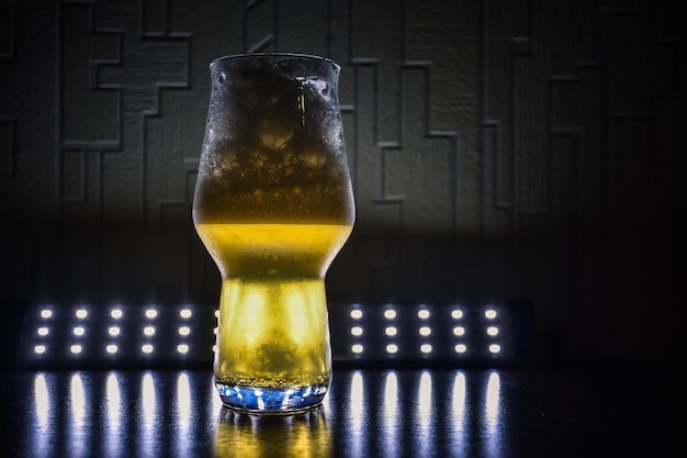 Zdjęcie wyróżnione szkło z piwnym zbliżeniem w ciemności na stole kręcone szkło z żółtym płynnym zbliżeniem