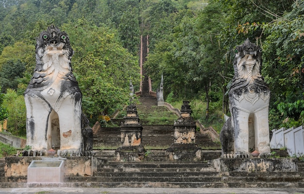Wyrzeźbiony birmański posąg lwów na schodach prowadzących na wzgórze w Wat Phra Non w Mae Hong Son w Tajlandii