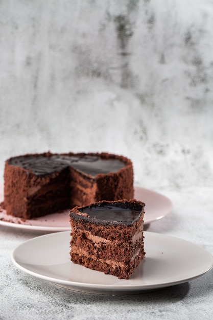 Wyśmienicie czekoladowy tort na talerzu na stole na marmurowym tle. Tapeta do cukierni lub menu kawiarni. pionowy.