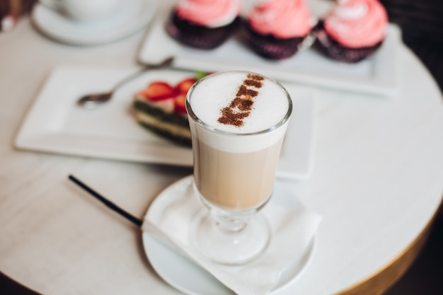 Wyśmienicie latte w szkle na stolik do kawy z babeczkami.