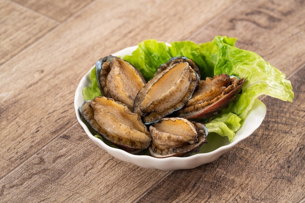 Wyśmienicie surowy abalone w talerzu na drewnianym stołowym tle