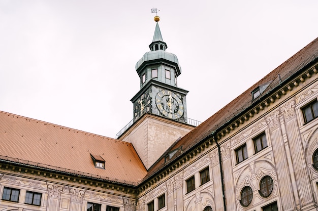 Wysoka iglica wieży monachijskiej rezydencji z zegarem na fasadzie