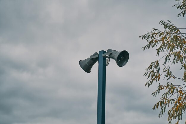 Zdjęcie wysoka metalowa kolumna z dwoma szarymi głośnikami zapewnia system ostrzegania przed niebezpieczeństwem w chmurnym niebie