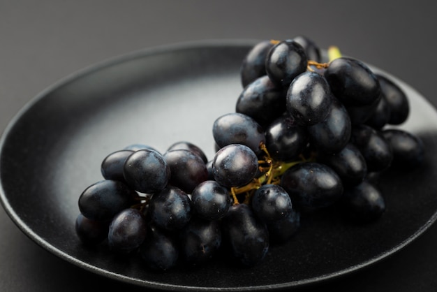 Zdjęcie wysoki kąt czarnych winogron na talerzu