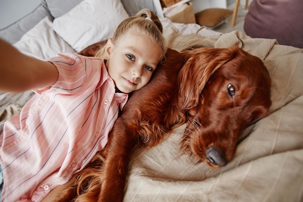 Wysoki Kąt Portret ślicznej Blondynki Biorącej Selfie Z Psem Na łóżku W Przytulnym Domu