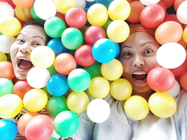 Zdjęcie wysoki kąt portretu szczęśliwych przyjaciół bawiących się kolorowymi piłkami