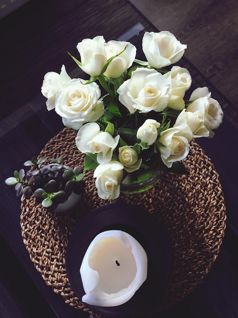 Zdjęcie wysoki kąt widoku białych róż przez świecę na stole