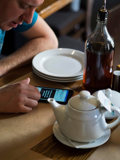 Zdjęcie wysoki kąt widoku dorosłego mężczyzny używającego telefonu na stole w restauracji