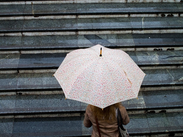 Wysoki kąt widoku kobiety niosącej parasol na schodach