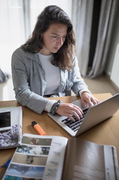 Wysoki kąt widoku kobiety używającej laptopa na stole, siedząc w domu
