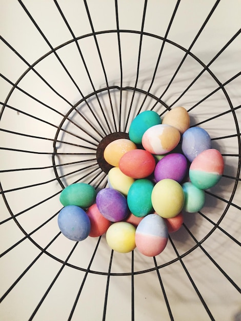 Zdjęcie wysoki kąt widoku kolorowych jajek wielkanocnych w koszu na stole