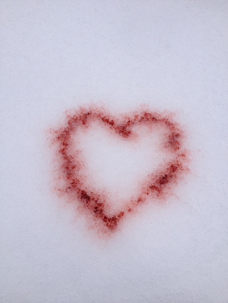 Zdjęcie wysoki kąt widoku kształtu serca w śniegu z czerwonym barwnikiem spożywczym