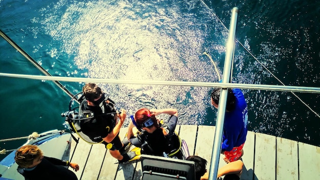 Zdjęcie wysoki kąt widoku ludzi noszących maskę nurkową stojących na łodzi nad morzem