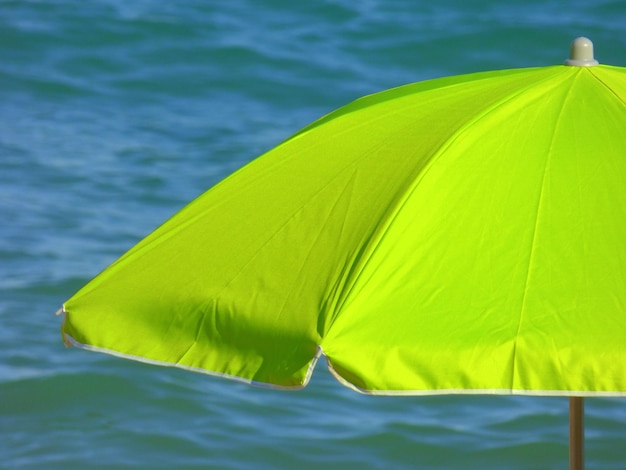 Zdjęcie wysoki kąt widoku otwartej zielonej parasoli na tle morza