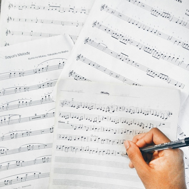Zdjęcie wysoki kąt widoku przyciętej ręki piszącej nuty muzyczne