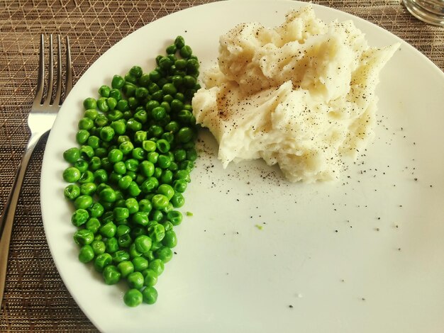 Zdjęcie wysoki kąt widoku puree ziemniaków z zielonym groszkiem na talerzu