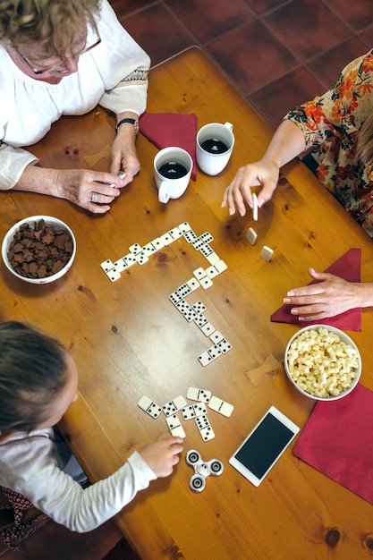 Wysoki Kąt Widoku Rodziny Grającej W Domino Podczas Jedzenia Na Stole