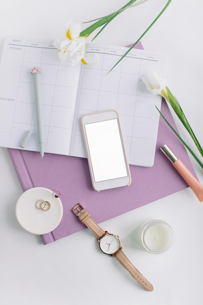 Zdjęcie wysoki kąt widoku smartfona i pamiętnika z osobistymi akcesoriami na stole
