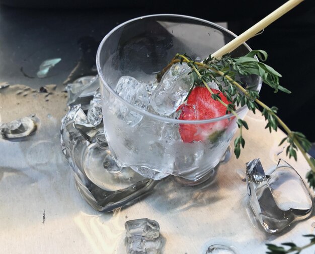 Zdjęcie wysoki kąt widoku szkła koktajlowego rozbitego na stole otoczonego lodowym alkoholem i złamanym szkłem