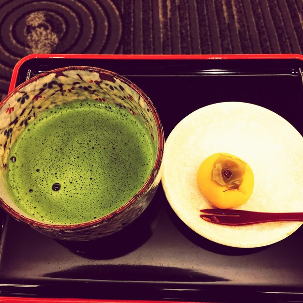 Zdjęcie wysoki kąt widoku zielonej herbaty i persimonu na tacce