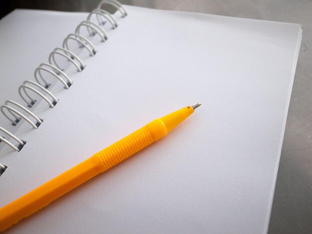 Zdjęcie wysoki kąt widoku żółtego długopisu na pustym spiralnym notatniku