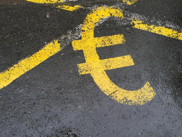 Zdjęcie wysoki kąt widoku żółtego symbolu euro na mokrej drodze
