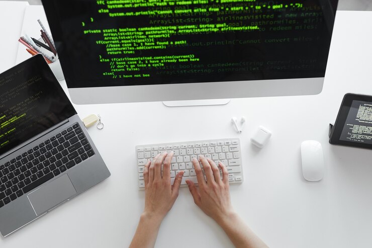 Zdjęcie wysoki kąt widzenia programisty piszącego na klawiaturze komputera instalującego nowy system na komputerze przy stole