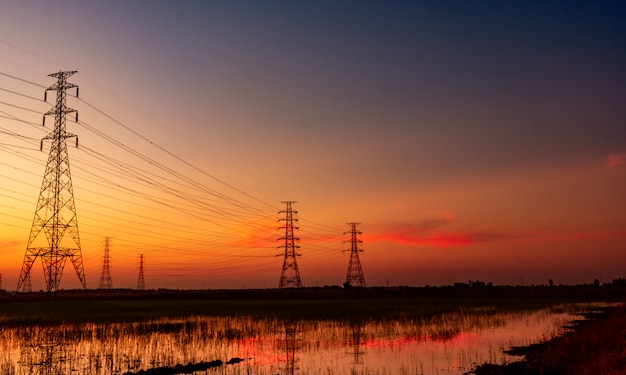 Wysoki woltaż elektryczny pilon i elektryczny drut z zmierzchu niebem. Słupy elektryczne. Pojęcie mocy i energii.