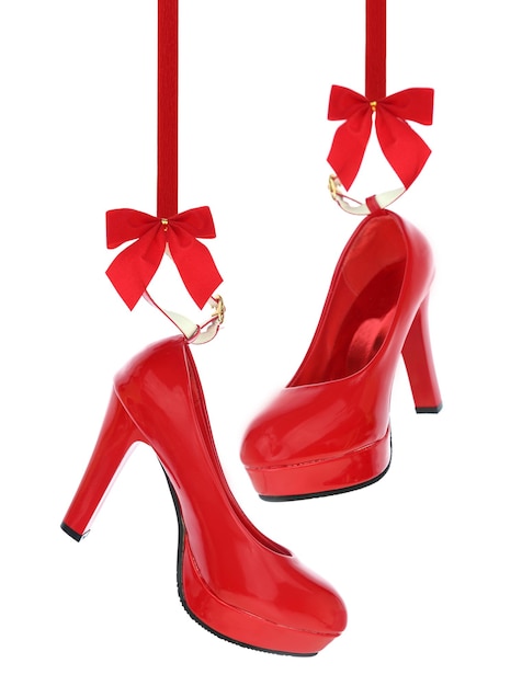Zdjęcie wysokie obcasy buty wiszące na czerwoną wstążką na białym tle