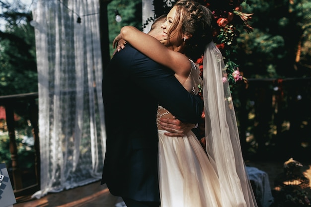 Wysokie oczyszczenie przytula delikatną błyszczącą pannę młodą, podczas gdy stoją przed ołtarzem weselnym