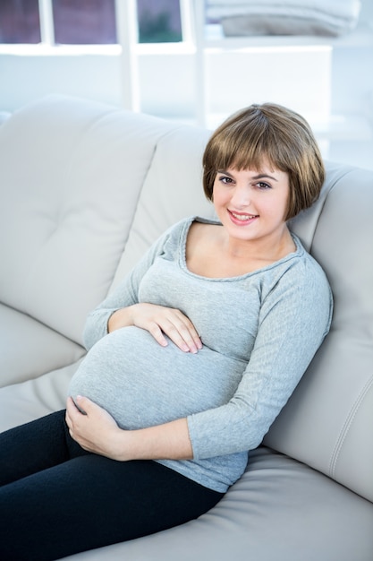 Zdjęcie wysokiego kąta widok uśmiechnięty kobieta w ciąży siedzi w domu