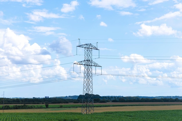 Wysoko napięciowa linia elektryczna wieża elektryczna na zielonym polu z niebieskim niebem