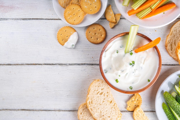 Wysokoproteinowy dip z serem wiejskim z świeżymi warzywami chleb i krakersy na drewnianym białym stole kopiowanie przestrzeni jedzenie diety zdrowy ser startowy rozłożony z różnymi przekąskami