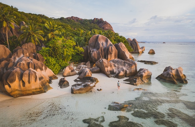 Wyspa „La digue” na Seszelach. Srebrna plaża z granitowym kamieniem i dżunglą. Mężczyzna cieszy się wakacje i relaksuje na plaży. Widok z lotu ptaka