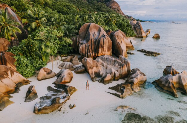 Wyspa „La digue” na Seszelach. Srebrna plaża z granitowym kamieniem i dżunglą. Mężczyzna cieszy się wakacje i relaksuje na plaży. Widok z lotu ptaka