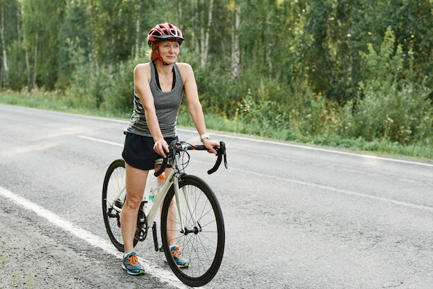 Wysportowana dziewczyna w kasku na rowerze sportowym na drodze na wsi