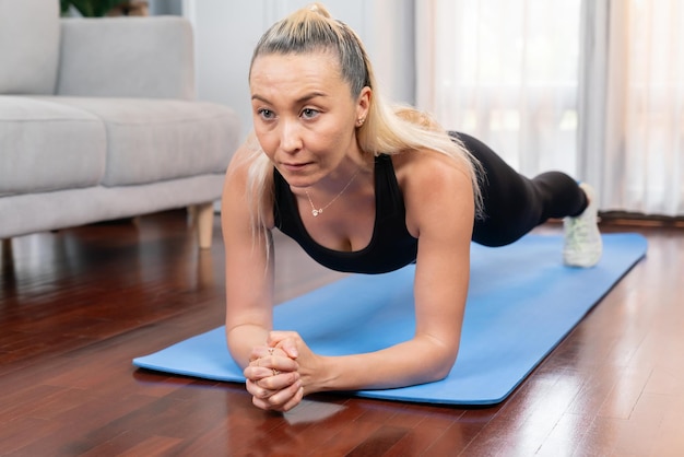 Wysportowana i sportowa starsza kobieta deska na macie do ćwiczeń fitness w domu ćwiczenia jako koncepcja zdrowego, sprawnego stylu życia ciała po przejściu na emeryturę Clout