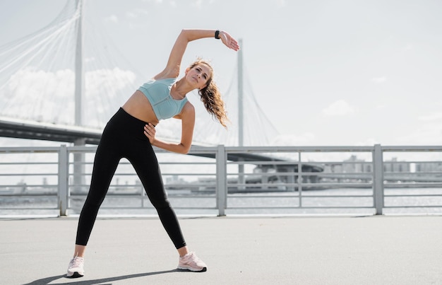 Wysportowana kobieta ćwiczy fitness na ulicy, inteligentny zegarek na ramieniu do treningu