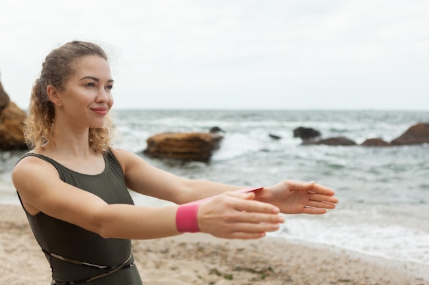 Wysportowana kobieta ćwiczy z gumkami fitness na plaży