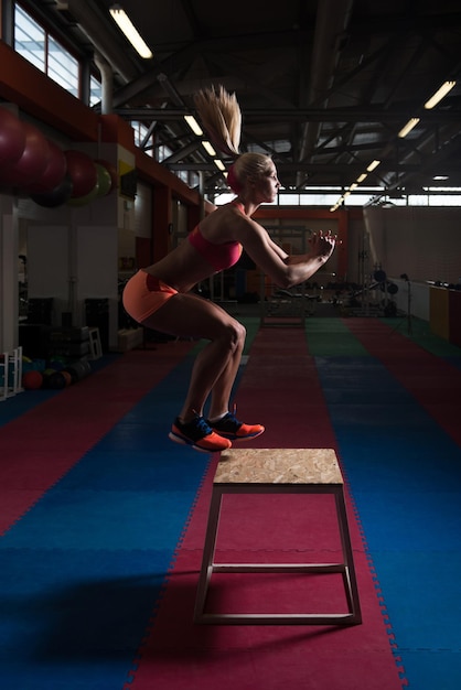 Wysportowana młoda kobieta skacze na siłowni w stylu bokserki Sportowiec wykonuje skoki na siłownię